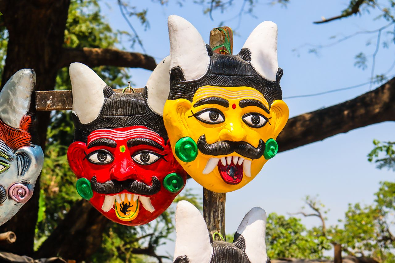 Colorful traditional masks with horns displayed on a sunny day.