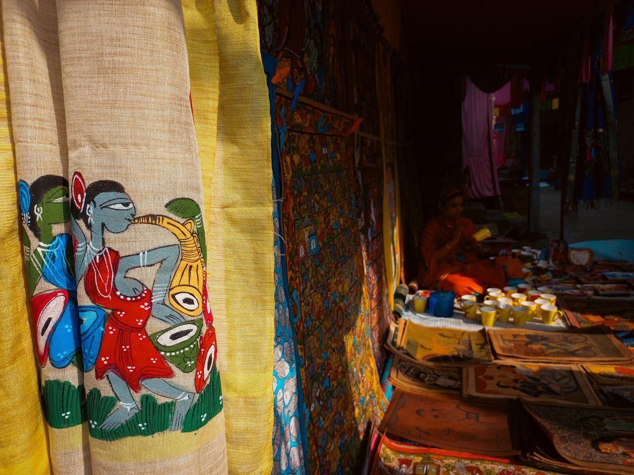 Colorful Indian textiles on display at a Midnapore market stall featuring intricate folk art designs.