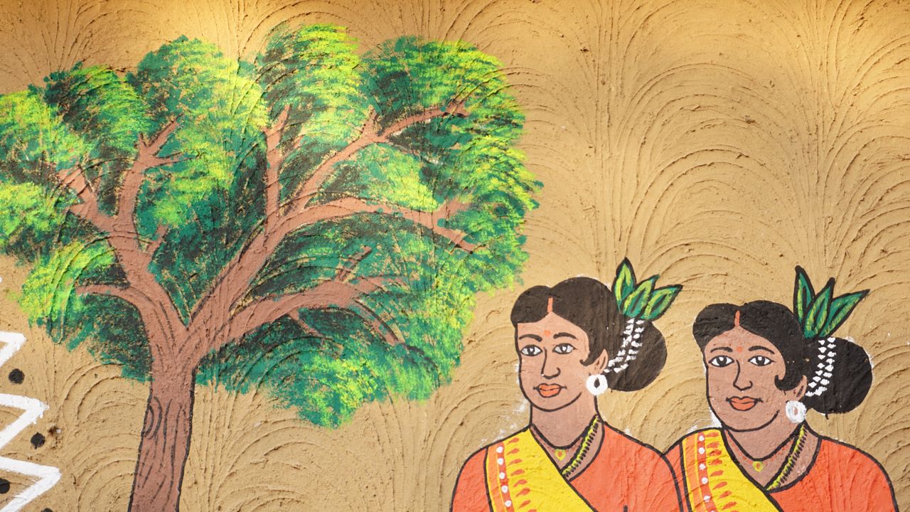 gallery-6 Vibrant mural showcasing Indian cultural elements with women in traditional attire and a tree.