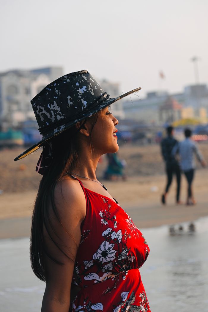 gallery-5 Portrait of a woman in a floral dress and hat standing by the beach in Puri, Odisha, India.
